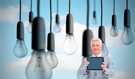 Composite image of mature businessman showing his tablet in front of big light bulbs in sky Photographie de stock - Aubaine LD & Abonnement, Code: 400-07180330