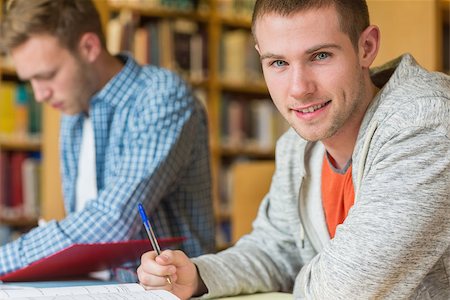 simsearch:400-07180633,k - Portrait of a smiling male student with a friend sitting at desk in the college library Foto de stock - Super Valor sin royalties y Suscripción, Código: 400-07180637