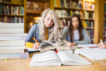 Two blurred students writing notes with stack of books at desk in the college library Stock Photo - Budget Royalty-Free & Subscription, Code: 400-07180630