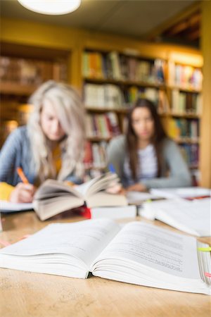 simsearch:400-07180633,k - Two blurred students writing notes at desk in the college library Foto de stock - Super Valor sin royalties y Suscripción, Código: 400-07180631