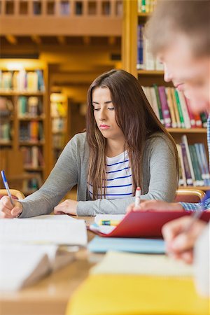 simsearch:400-07180633,k - Young female student writing notes at desk in the college library Foto de stock - Super Valor sin royalties y Suscripción, Código: 400-07180632