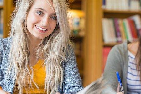 simsearch:400-08650429,k - Portrait of a smiling female student in the college library Photographie de stock - Aubaine LD & Abonnement, Code: 400-07180646