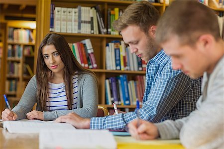 simsearch:400-07180633,k - Portrait of a smiling female student with friends sitting at desk in the college library Foto de stock - Super Valor sin royalties y Suscripción, Código: 400-07180642