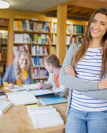 simsearch:400-07180633,k - Portrait of a smiling female student with others in background in the college library Foto de stock - Super Valor sin royalties y Suscripción, Código: 400-07180658