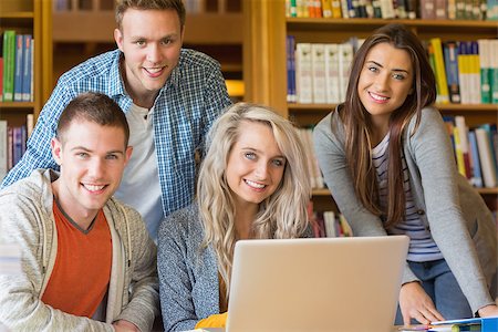 simsearch:400-07180633,k - Group portrait of four happy students using laptop at desk in the college library Foto de stock - Super Valor sin royalties y Suscripción, Código: 400-07180677