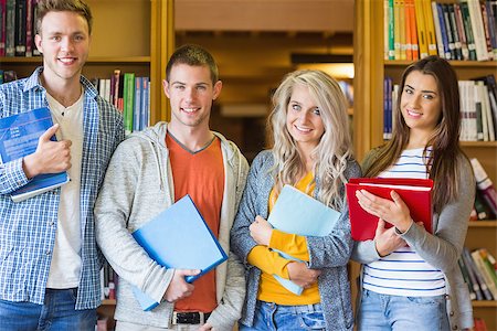 simsearch:400-07180633,k - Group portrait of four students with folders standing against bookshelf in the college library Foto de stock - Super Valor sin royalties y Suscripción, Código: 400-07180683