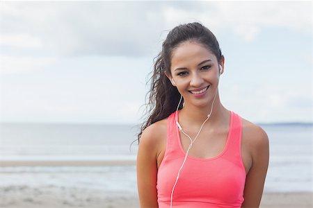simsearch:400-07180905,k - Portrait of a smiling healthy woman with earphones standing on beach Photographie de stock - Aubaine LD & Abonnement, Code: 400-07180896