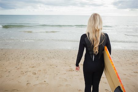 Rear view of a young woman in wet suit holding surfboard at beach Stock Photo - Budget Royalty-Free & Subscription, Code: 400-07180986