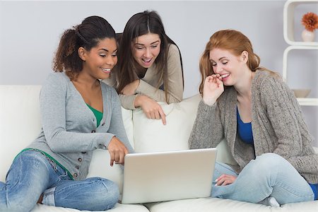 simsearch:400-07181183,k - Cheerful young female friends using laptop together on sofa at home Photographie de stock - Aubaine LD & Abonnement, Code: 400-07181108