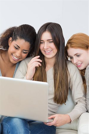 simsearch:400-07181183,k - Cheerful young female friends using laptop together on sofa at home Photographie de stock - Aubaine LD & Abonnement, Code: 400-07181137