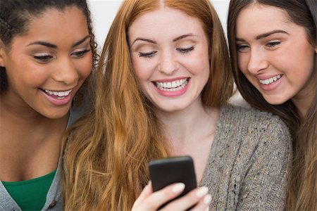simsearch:400-07181183,k - Close up of cheerful young female friends looking at mobile phone together at home Photographie de stock - Aubaine LD & Abonnement, Code: 400-07181131