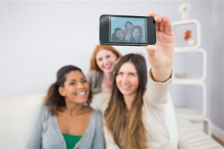 simsearch:400-07181183,k - Happy young female friends photographing themselves with smartphone on sofa at home Photographie de stock - Aubaine LD & Abonnement, Code: 400-07181140