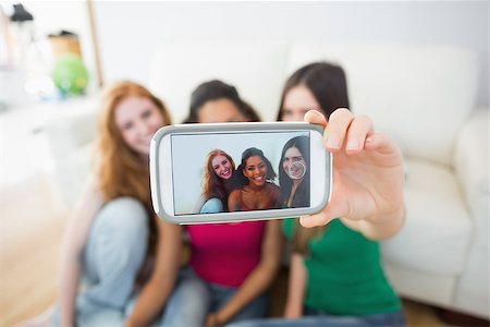 simsearch:400-07181183,k - Happy young female friends photographing themselves with smartphone on floor at home Photographie de stock - Aubaine LD & Abonnement, Code: 400-07181179