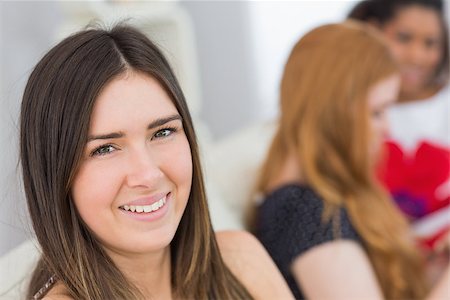 simsearch:400-07181183,k - Portrait of a brunette with young female friends on sofa in background Photographie de stock - Aubaine LD & Abonnement, Code: 400-07181172