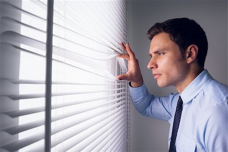 Side view of a young businessman peeking through blinds in office Stock Photo - Budget Royalty-Free & Subscription, Code: 400-07181485