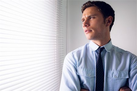 Elegant young businessman peeking through blinds in office Stock Photo - Budget Royalty-Free & Subscription, Code: 400-07181489