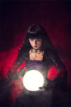 simsearch:400-07209173,k - Beautiful gothic style fortune teller with a crystal ball, studio shot over smoky background Fotografie stock - Microstock e Abbonamento, Codice: 400-07209173