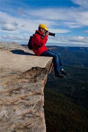 Tourist or photographer on a cliff edge taking photos  of a mountainous landscape Photographie de stock - Aubaine LD & Abonnement, Code: 400-07209182