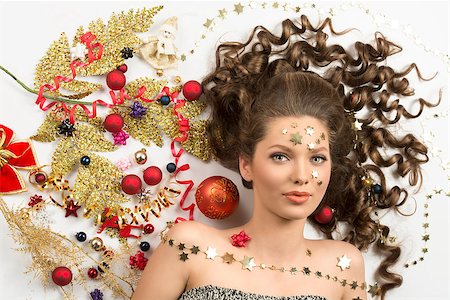 simsearch:400-07223828,k - christmas beauty close-up portrait of sensual curly brunette girl with splendid eyes surrounded by colorful xmas decorations, red baubles, golden branch, ribbon and stars on her face. Fotografie stock - Microstock e Abbonamento, Codice: 400-07216206