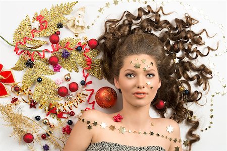 simsearch:400-07223828,k - creative christmas shoot with splendid curly brunette female with golden stars make-up surrounded by some xmas colorful decorations. Red baubles, golden branch, stars and ribbon Fotografie stock - Microstock e Abbonamento, Codice: 400-07216207