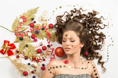 simsearch:400-07223828,k - sensual young girl lying with long curly brown hair and naked shoulder surrounded by various funny christmas decorations. Red and colorful baubles, ribbon, golden stars and branch. Creative xmas close-up shoot Fotografie stock - Microstock e Abbonamento, Codice: 400-07216208