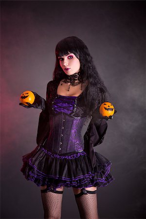 simsearch:400-07209173,k - Pretty witch in purple Halloween costume holding Jack-o-lantern style oranges Fotografie stock - Microstock e Abbonamento, Codice: 400-07210683