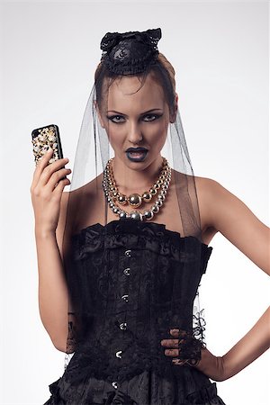 simsearch:400-07223828,k - sensual blonde girl with halloween style and make-up wearing gothic dress and dark veil on the face and taking smartphone in the hand Fotografie stock - Microstock e Abbonamento, Codice: 400-07211715