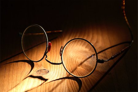Closeup of old spectacles with long shadow on wooden surface Foto de stock - Super Valor sin royalties y Suscripción, Código: 400-07212123