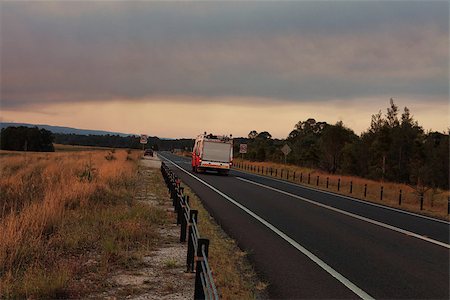 fire help - A  Rural Fire Service, fire and rescue vehicle responds urgently to a large out of control bushfire in the mountains.  Smoke and sun casts a red glow across the landscape Stock Photo - Budget Royalty-Free & Subscription, Code: 400-07212505