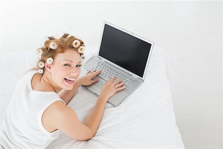 simsearch:693-06120730,k - High angle portrait of a cheerful young woman in hair curlers using laptop in bed at home Foto de stock - Super Valor sin royalties y Suscripción, Código: 400-07227969