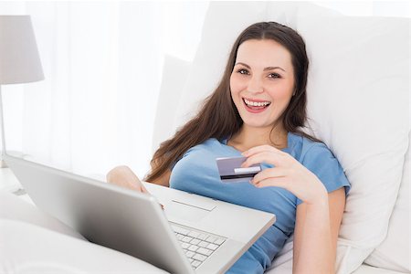 simsearch:6109-06194946,k - Cheerful casual young woman doing online shopping through laptop and credit card in bed Fotografie stock - Microstock e Abbonamento, Codice: 400-07228001