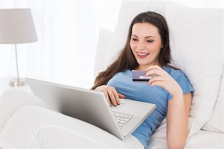 simsearch:6109-06194946,k - Cheerful casual young woman doing online shopping through laptop and credit card in bed Fotografie stock - Microstock e Abbonamento, Codice: 400-07228002