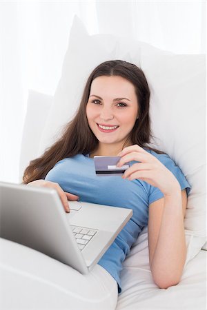 simsearch:400-07268814,k - Casual young woman doing online shopping through laptop and credit card in bed Foto de stock - Royalty-Free Super Valor e Assinatura, Número: 400-07228003
