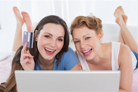simsearch:6109-06194946,k - Portrait of cheerful relaxed young female friends  doing online shopping through laptop and credit card in bed Fotografie stock - Microstock e Abbonamento, Codice: 400-07228025