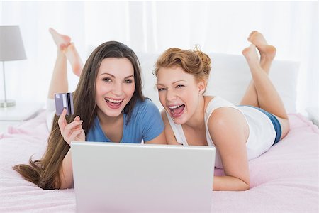 simsearch:6109-06194946,k - Portrait of cheerful relaxed young female friends  doing online shopping through laptop and credit card in bed Fotografie stock - Microstock e Abbonamento, Codice: 400-07228028