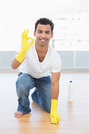 simsearch:400-07228658,k - Portrait of a smiling young man cleaning the floor while gesturing okay sign at house Stockbilder - Microstock & Abonnement, Bildnummer: 400-07228659