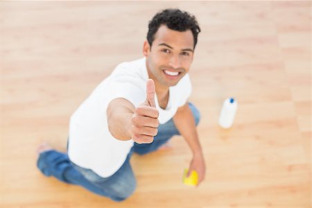simsearch:400-07228658,k - Portrait of a smiling young man cleaning the floor while gesturing thumbs up at house Stockbilder - Microstock & Abonnement, Bildnummer: 400-07228650
