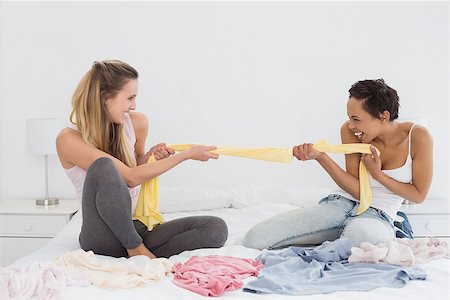 Two pretty female friends jokingly fighting over clothes on bed at home Stock Photo - Budget Royalty-Free & Subscription, Code: 400-07228841