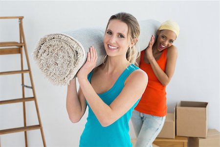 Portrait of two smiling female friends carrying rolled rug after moving in a house Stock Photo - Budget Royalty-Free & Subscription, Code: 400-07229031