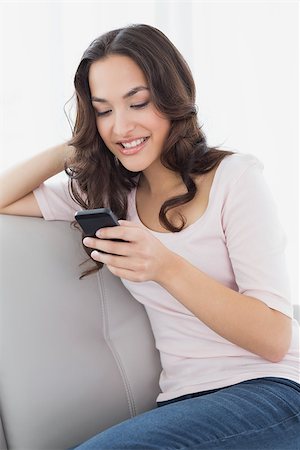 simsearch:400-08054488,k - Relaxed young woman text messaging on sofa in living room at home Stock Photo - Budget Royalty-Free & Subscription, Code: 400-07229125