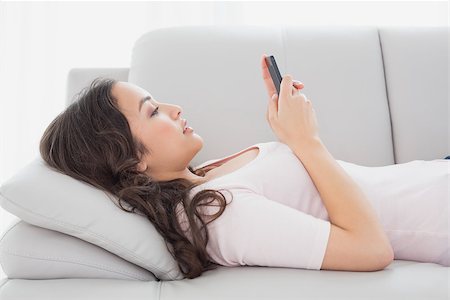 simsearch:400-08054488,k - Side view of a relaxed young woman text messaging on sofa in living room at home Stock Photo - Budget Royalty-Free & Subscription, Code: 400-07229128