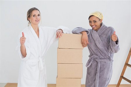 Portrait of two smiling female friends in bathrobes with boxes gesturing thumbs up in a new house Stock Photo - Budget Royalty-Free & Subscription, Code: 400-07229120