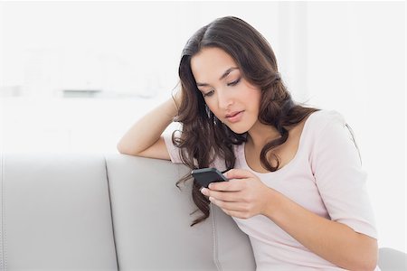 simsearch:400-08054488,k - Relaxed young woman text messaging on sofa in living room at home Stock Photo - Budget Royalty-Free & Subscription, Code: 400-07229122