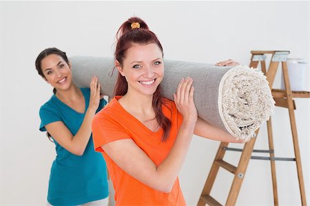 Portrait of two smiling female friends carrying rolled rug after moving in a house Stock Photo - Budget Royalty-Free & Subscription, Code: 400-07229364