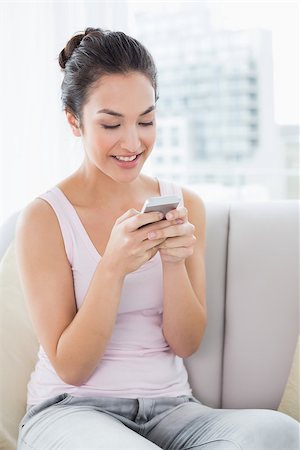 simsearch:400-08054488,k - Relaxed young woman text messaging on sofa in living room at home Stock Photo - Budget Royalty-Free & Subscription, Code: 400-07229584