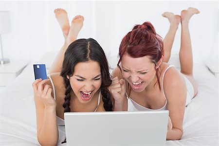 simsearch:6109-06194946,k - Cheerful relaxed young female friends doing online shopping through laptop and credit card in bed Fotografie stock - Microstock e Abbonamento, Codice: 400-07229582