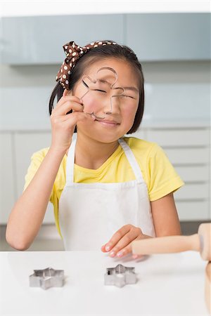 Portrait of a smiling young girl holding cookie mold in the kitchen at home Stock Photo - Budget Royalty-Free & Subscription, Code: 400-07229754