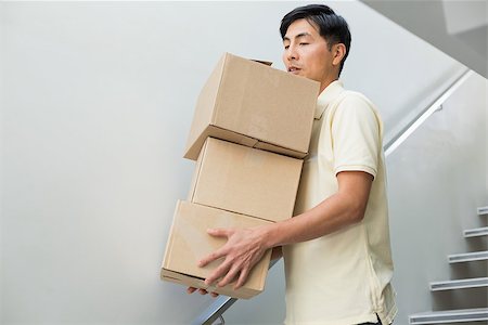 Low angle view of a young man carrying boxes against staircase Stock Photo - Budget Royalty-Free & Subscription, Code: 400-07229867