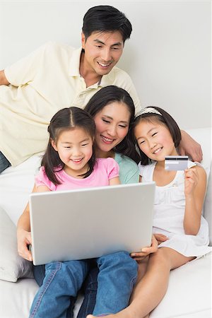 simsearch:400-07333971,k - Happy family of four doing online shopping through laptop and credit card at home Stock Photo - Budget Royalty-Free & Subscription, Code: 400-07229887