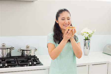 person standing and eating pizza - Smiling young woman eating a slice of pizza in the kitchen at home Photographie de stock - Aubaine LD & Abonnement, Code: 400-07229935